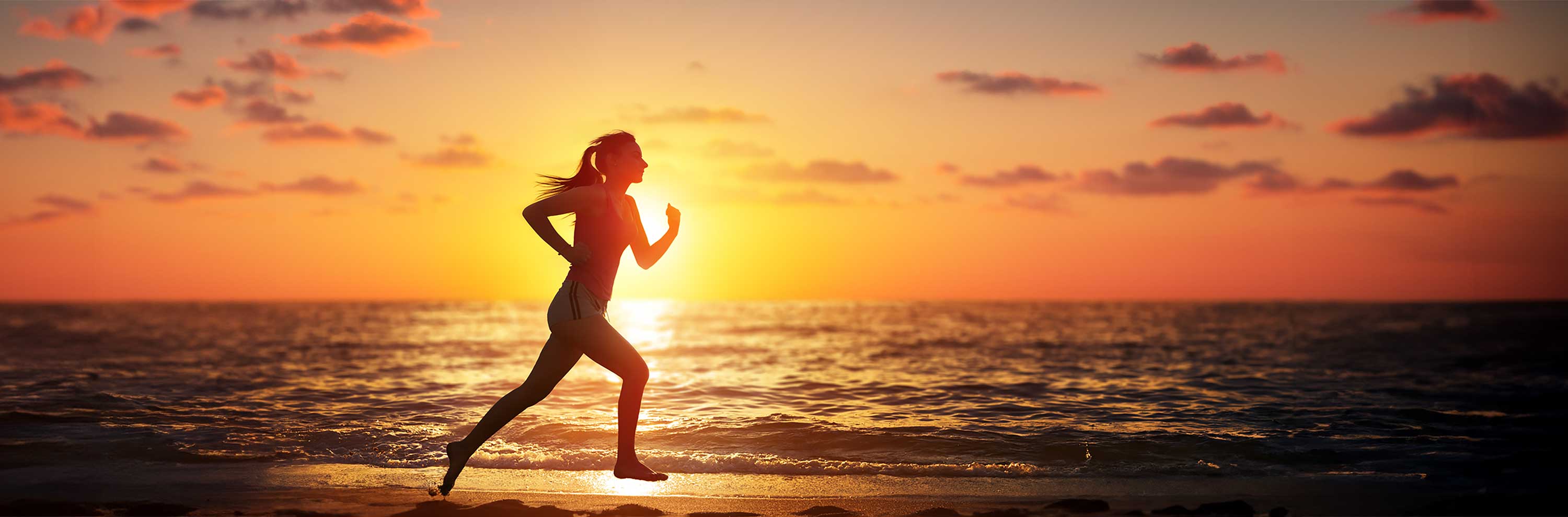 Photo of a runner on the beach at sunset